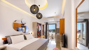 Habitació d'hotel moderna amb un llit gran, una taula de treball amb cadira, televisió, armari i un balcó amb vistes.
