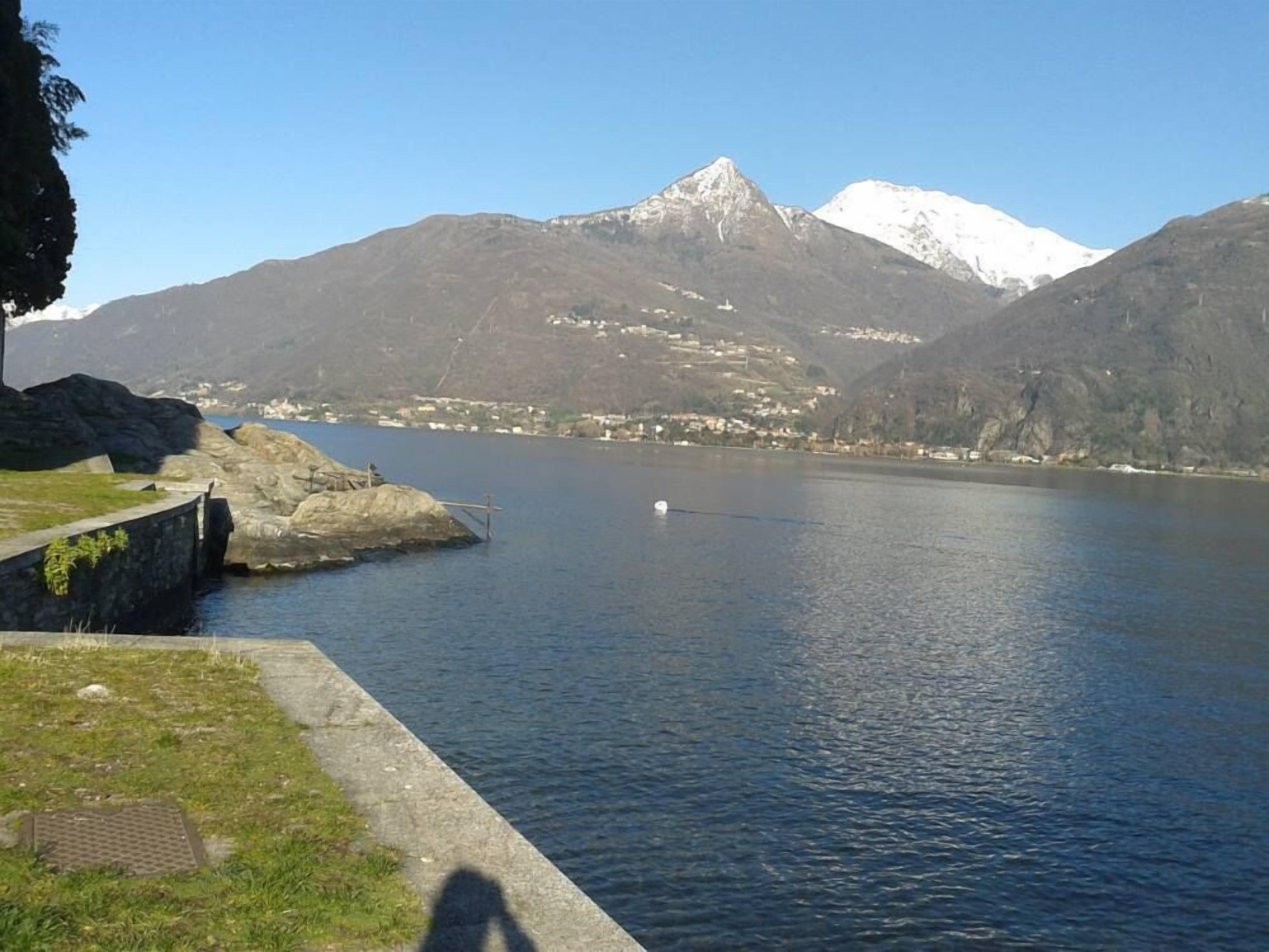 Ein ruhiger See mit steiniger Uferlinie und einem fernen Gebirge.