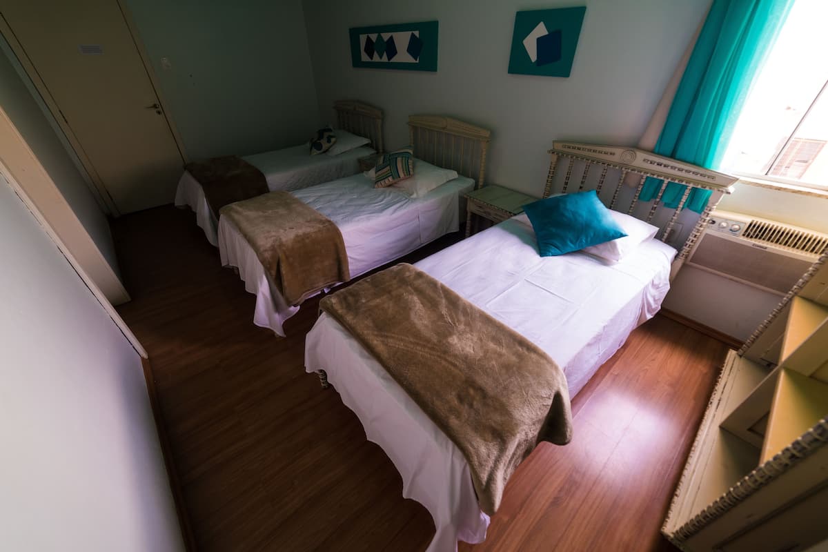Habitació amb dos llits individuals, terres de fusta, una petita taula de nit i un radiador.