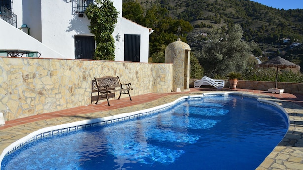 A swimming pool with stone tiles, a bench, and a stone wall. - Luxurious 'finca' With Private Pool In The 'campo' (Cómpeta)