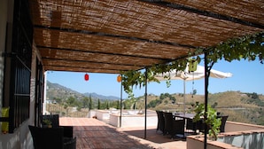 A covered outdoor patio with a table and chairs, a view of the countryside, and a pergola with hanging plants. - Luxurious 'finca' With Private Pool In The 'campo' (Cómpeta)