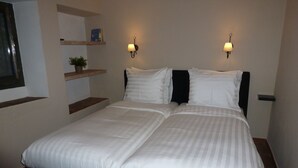 A neatly made bed with white bedding, two wall-mounted lamps, and a small shelf with a plant. - Luxurious 'finca' With Private Pool In The 'campo' (Cómpeta)