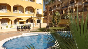 Un hotel con piscina circondata da palme e una zona patio con sedie.