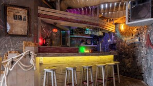 A bar area with wooden stools, a neon sign, and a rustic stone wall. - Villa With  Best Amazing Ocean Views (Santa Úrsula)