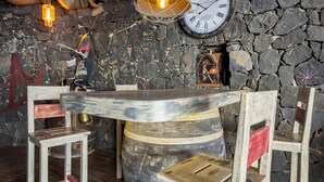 A rustic interior with a stone wall, wooden chairs, a round wooden table, and a wall clock. - Villa With  Best Amazing Ocean Views (Santa Úrsula)
