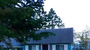 Une maison à deux étages avec une porte rouge, des volets blancs et une façade bleue.