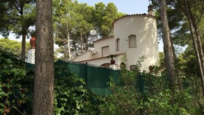 Ein weißes Gebäude mit einem runden Turm, umgeben von Bäumen und einem grünen Zaun.