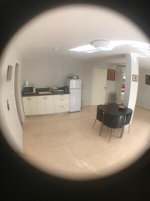 Compact kitchen area with a dining table and chairs, microwave, and refrigerator.
