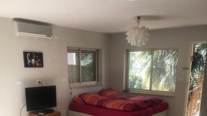 Un dormitorio con cama, televisor y ventana.