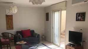 Una sala de estar con sofá, mesa de centro, televisor y cama.