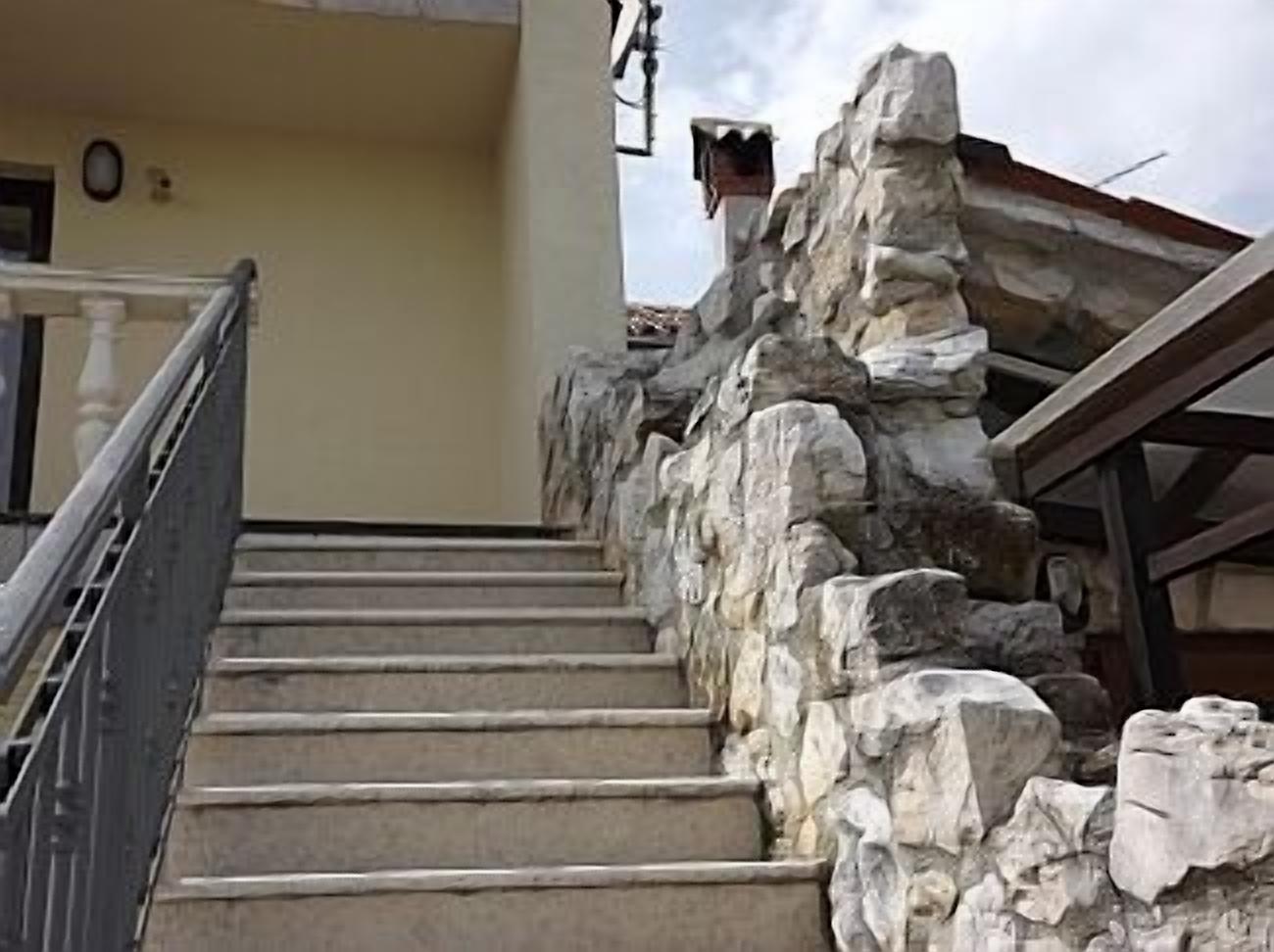 A staircase with stone steps and a metal railing, leading to a building entrance.
