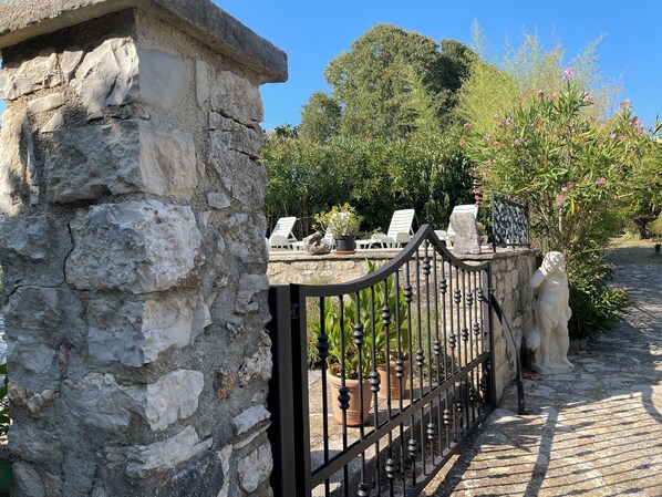 A stone wall with a metal gate, potted plants, and outdoor seating. - Villa With Swimming Pool In An Picturesque Istrian Village (Vrsar)