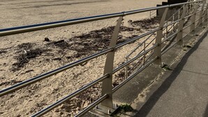 A beach with a concrete walkway and a building in the background.