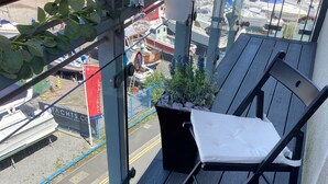 A balcony with a wooden table, a bottle of wine, and a glass of wine.