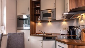 Una kitchenette compacta con microondas, horno y lavamanos.