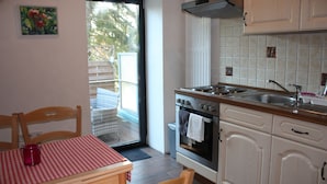 A kitchen with a dining area, a view through a glass door, and a painting on the wall. - Suite with terrace and view of the church, lake access - Ferienhof Löschebrand (Bad Saarow)