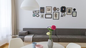 Ein modernes Wohnzimmer mit einem grauen Sofa, einem weißen Tisch mit zwei Schüsseln und einer Vase mit Blumen.