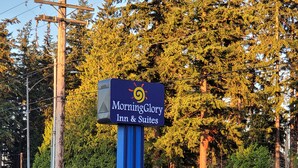 A parking lot with a sign for Morning Glory Inn & Suites, indicating the entrance.