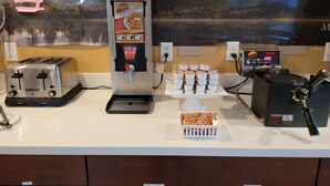A breakfast station with a coffee machine, a toaster, and a waffle maker.
