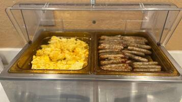 A buffet with scrambled eggs and sausages.