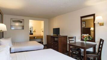 Een hotelkamer met twee bedden, een bureau, een stoel, een televisie en een spiegel.