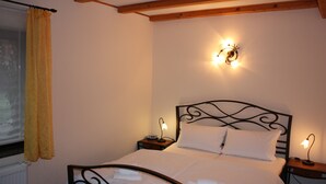 A bedroom with a bed, two bedside tables, a wall-mounted light fixture, and a window with curtains. - Studio with winter garden and lake view - Ferienhof Löschenrand (Bad Saarow)