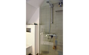 Et moderne badeværelse med en glasbrusekabine, toilet og håndvask.