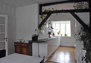 A modern kitchen with white cabinets, a wooden dining table, and a window with a view of the outside.