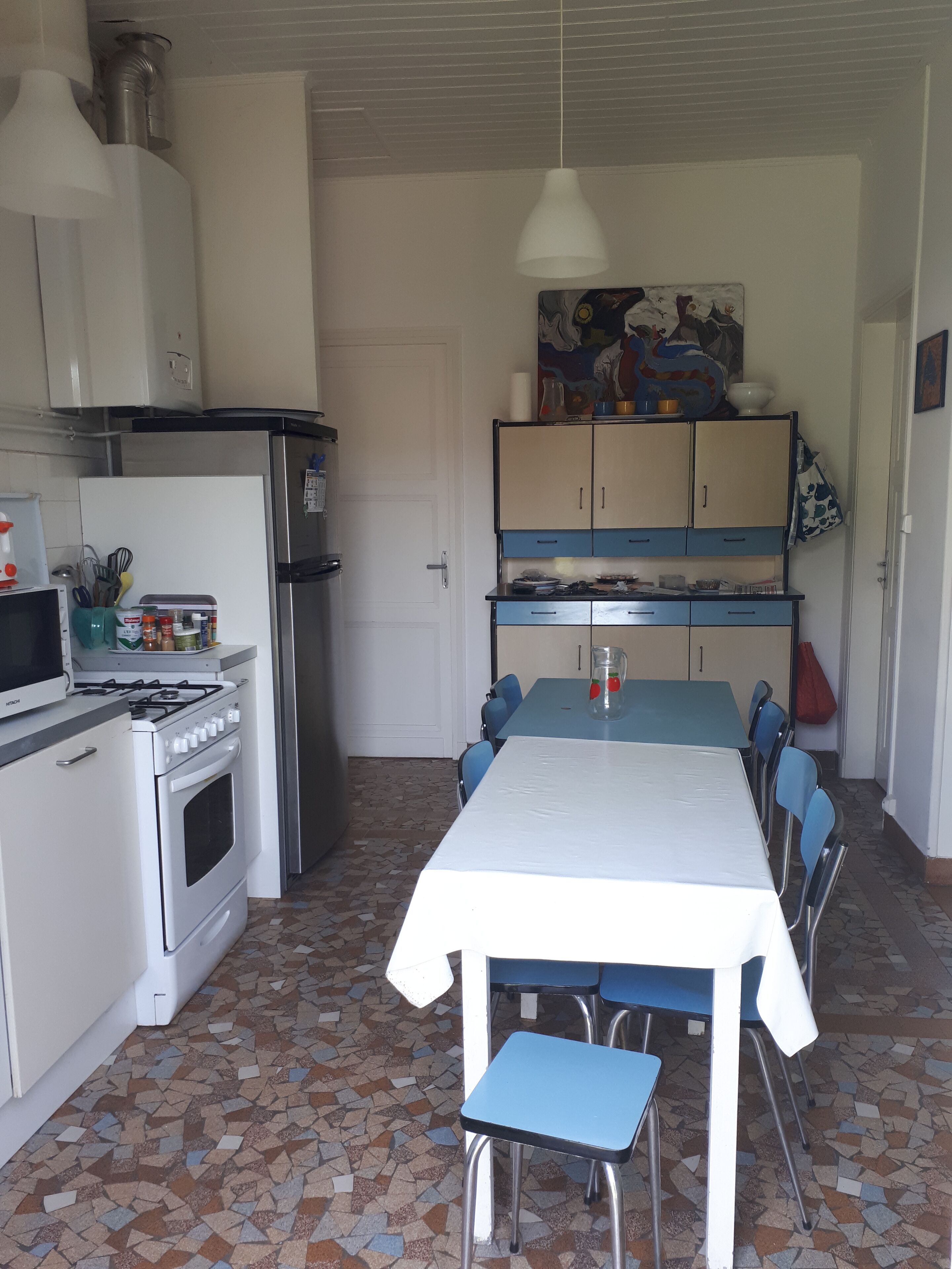 A compact kitchen with a stove, refrigerator, and dining table with chairs.
