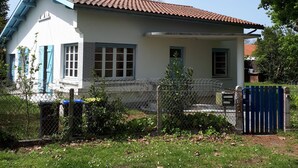 Une maison de plain-pied avec un toit en tuiles, une cour clôturée et une boîte aux lettres.