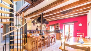 Una cocina amplia con una isla central, taburetes de madera y una escalera en espiral.