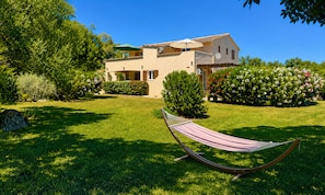 A house with a garden, a hammock, and a clear blue sky.