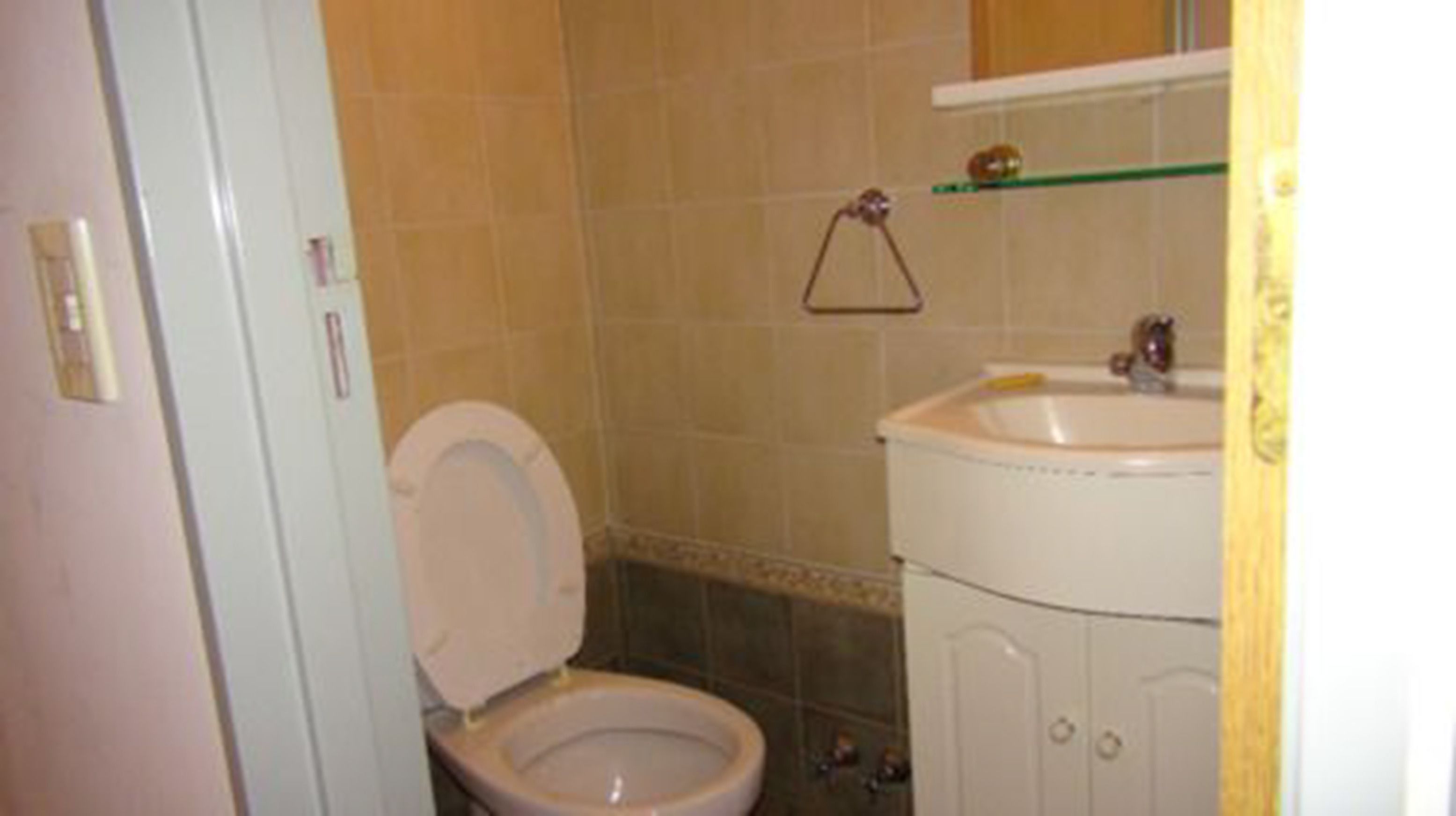 A bathroom with a toilet, sink, and tiled walls.