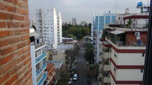 A cityscape with multi-story buildings, a narrow street, and parked cars. - Sunny 2 Bedroom Apartment (Buenos Aires)