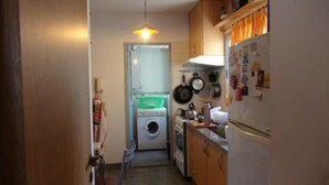 A compact kitchen with a washing machine, a refrigerator, and a hanging pot rack. - Sunny 2 Bedroom Apartment (Buenos Aires)