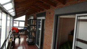 A room with a wooden ceiling, brick walls, a large window, and a door leading to another room. - Sunny 2 Bedroom Apartment (Buenos Aires)