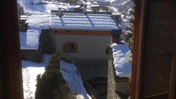 A snowy mountain village with traditional buildings and a clear view of the surrounding peaks. - Authentic home, combining the warmth of wood and mountain stone.  (Les Belleville)