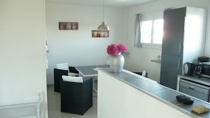 A compact kitchen with a dining area, a refrigerator, and a microwave.