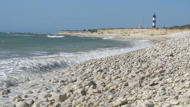 A rocky beach with a lighthouse in the background.