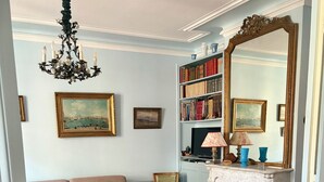 Ein Wohnzimmer mit Sofa, Sesseln, Kamin, Bücherregal und einer Chandelier.