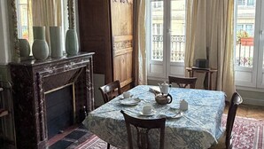 Ein Esszimmer mit Marmorofen, einem Chandelier und Blick auf die Straße durch große Fenster.