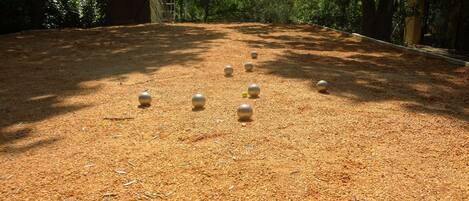 A courtyard with a wooden fence, a sandy ground, and several spherical objects.