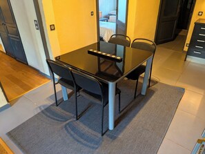A hotel room with a dining table, chairs, a small rug, and a view of a bed through an open door. - 100% quiet in Uzès! pool 10X5m, 70m² with AC + private terrace, WIFI, big garden (Uzès)