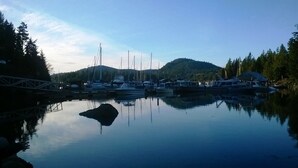 Uma marina com barcos atracados, uma ponte e uma montanha ao fundo.