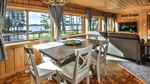 Une cabane en bois comprenant un coin repas, un canapé et un téléviseur.