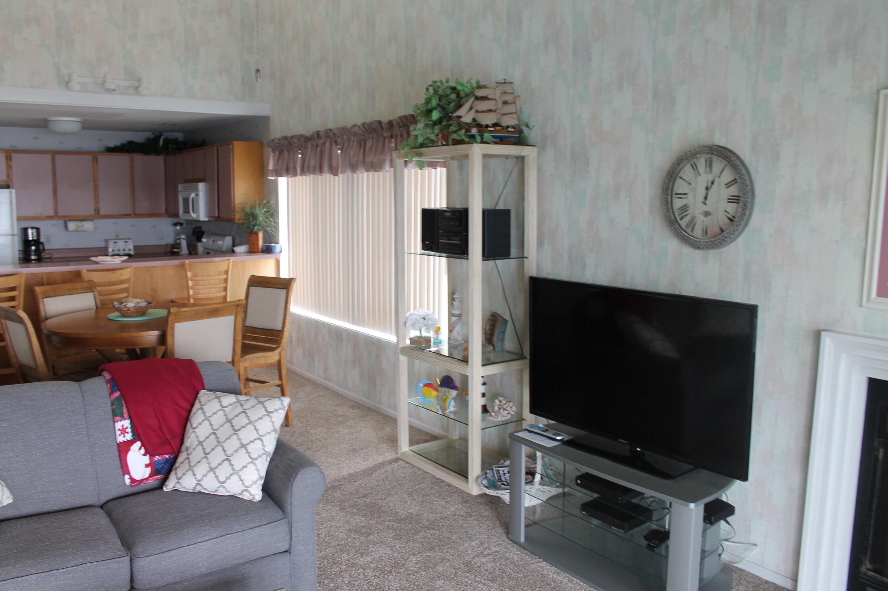 A living room with a grey sofa, a television, and a glass cabinet with decorative items.