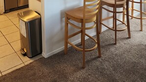 Een moderne keuken met witte kasten, roestvrijstalen apparatuur en een centraal eiland met barstoelen.