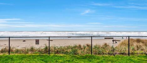 A fenced beach area with a clear view of the ocean.