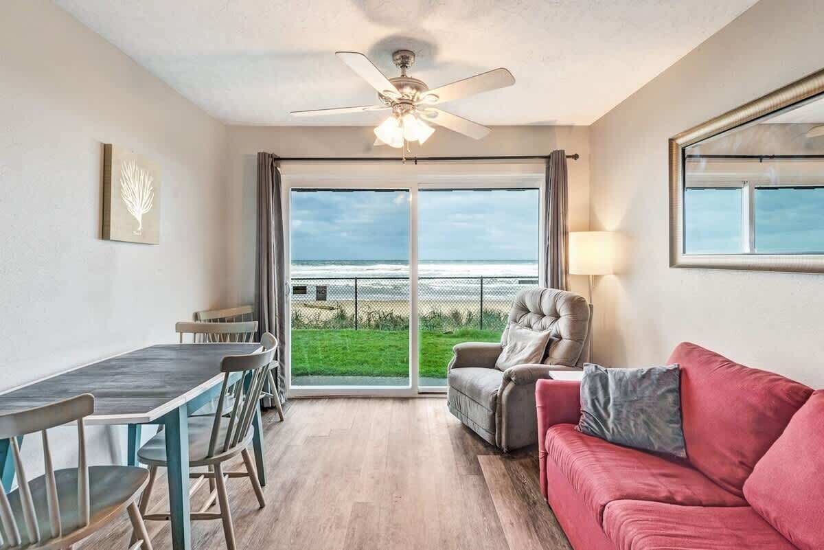 Une pièce comprenant une table à manger, des chaises, un canapé rouge, un fauteuil gris et un ventilateur de plafond.