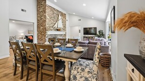 Un comedor con una pared de ladrillo decorativa, una decoración de velero y un televisor moderno al fondo.